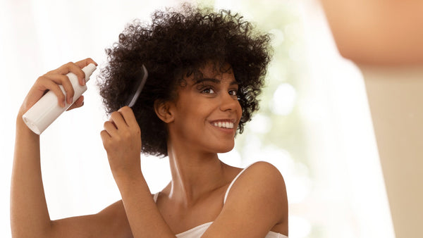 foto ilustrativa de mulher passando um produto no cabelo e penteando