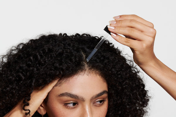 Imagem de mulher aplicando blend de óleos do Mariá Head & Hair no couro cabeludo